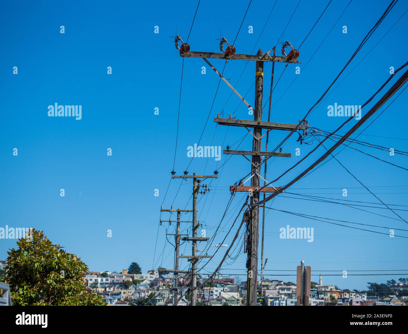 Zeichenkette von Power Utility pools stringing Netzkabel an Wohngebäuden an einem sonnigen Tag Stockfoto