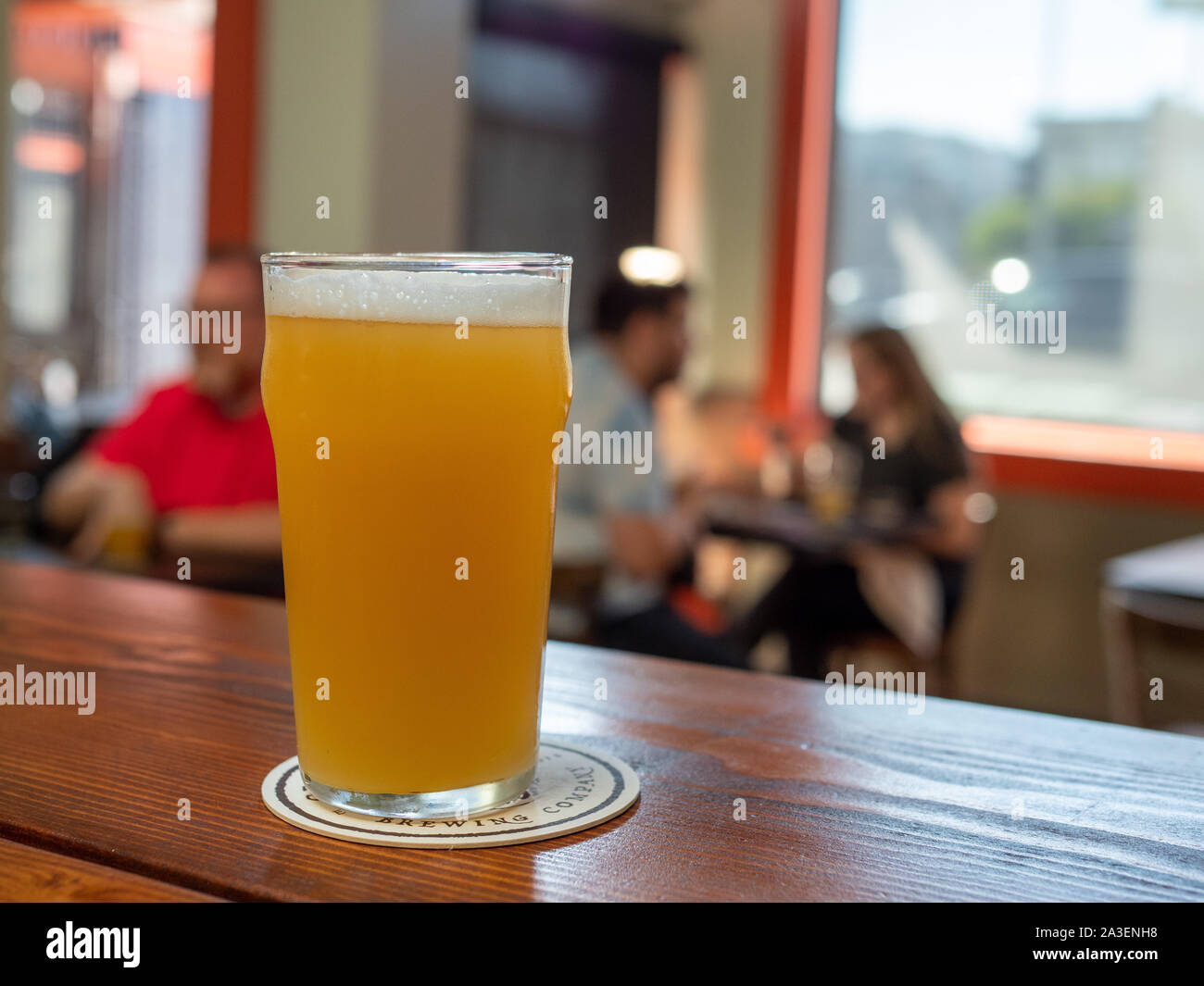 Volle pint Glas IPA Bier sitzen auf hölzernen Tisch Brauerei Restaurant mit Menschen im Hintergrund Stockfoto