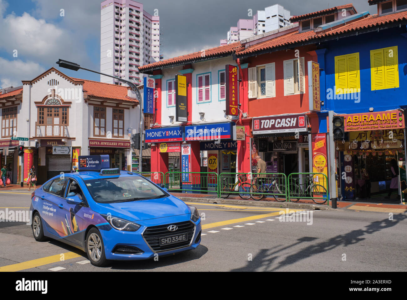 Mehrfarbige renoviert Geschäftshäuser in der Serangoon Road, Little India, Singapur, mit einem blauen Taxi vorbei vor Stockfoto