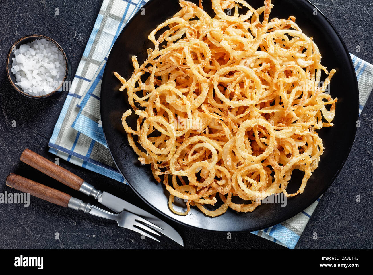 In der Nähe von französischen knusprig gebratenen Zwiebeln und Streicher auf einer schwarzen Platte auf einer konkreten Tabelle Stockfoto