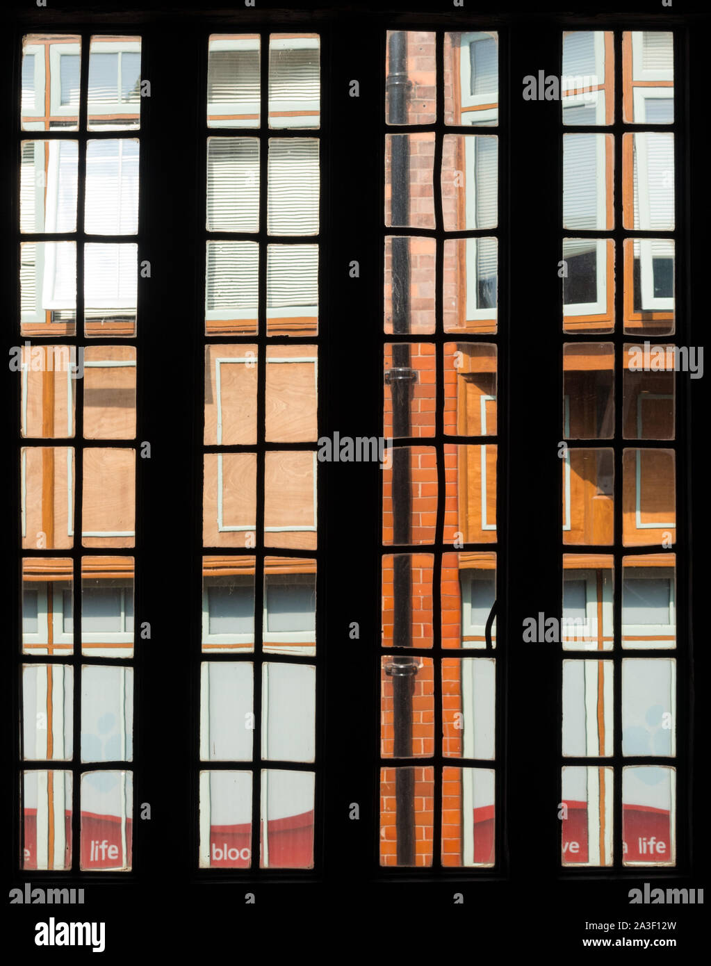 Blick durch alte Bleiglasfenstern von Leicester Guildhall bei neueren Gebäude außerhalb der Guildhall, Leicester, England, Großbritannien Stockfoto
