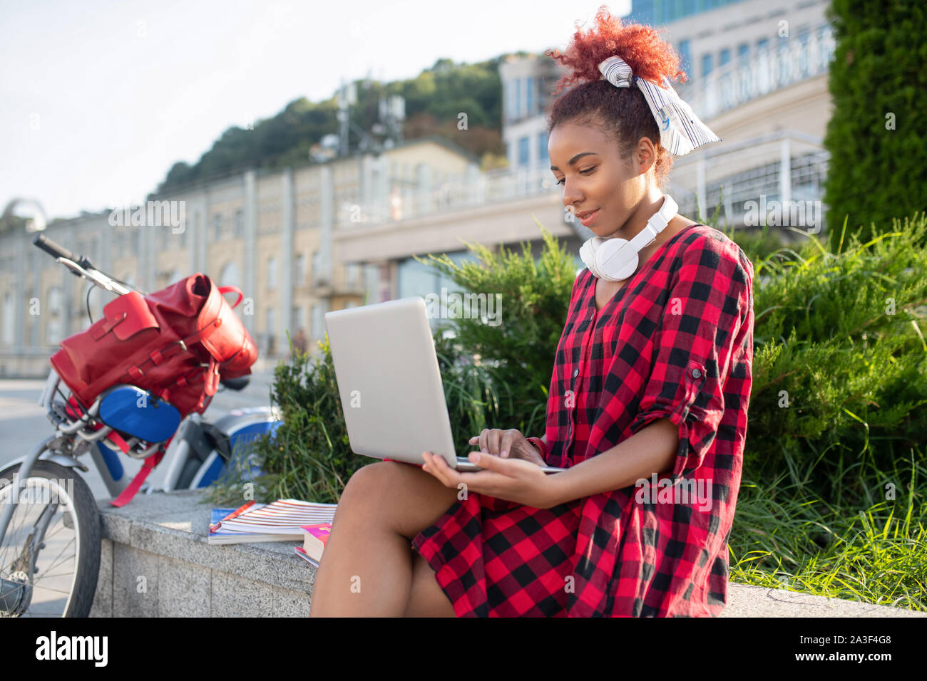 Rothaarige Studentin genießen online Lektion während draußen sitzen Stockfoto
