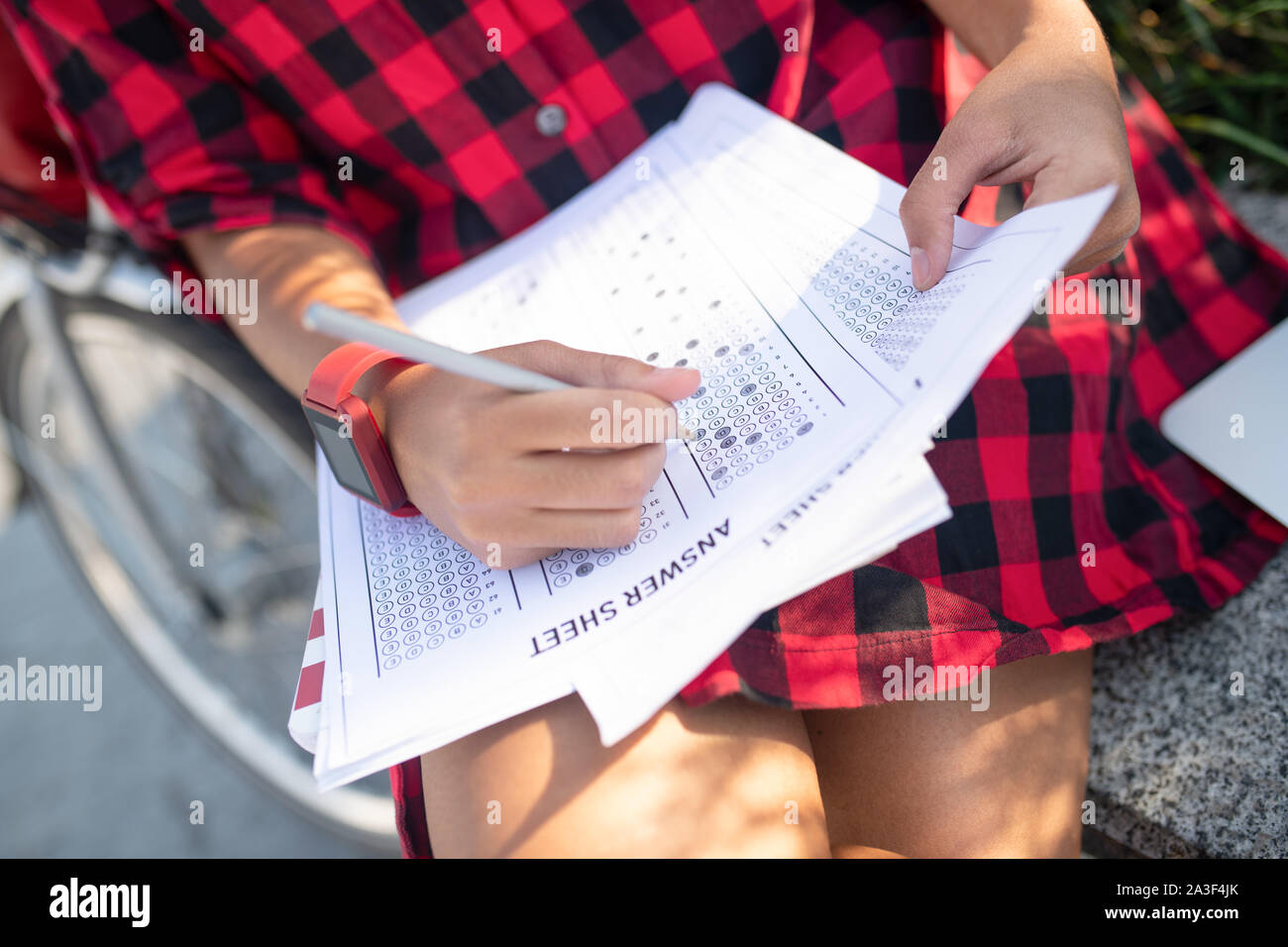 Student trägt Rot kariertes Hemd schreiben Antworten für Test Stockfoto