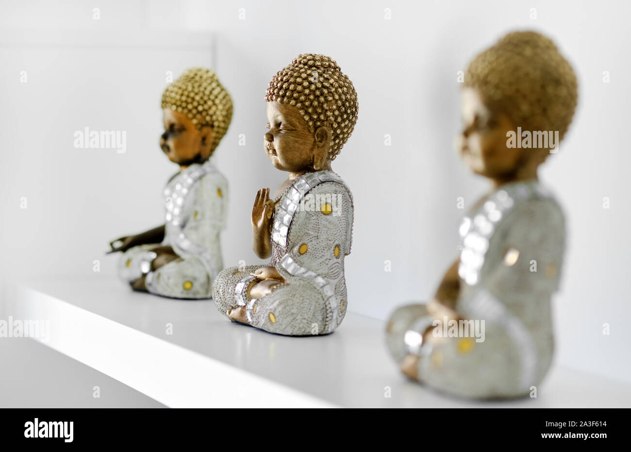 Drei kleine dekorative Buddha Figuren auf dem Regal im Zimmer in einer Reihe Stockfoto