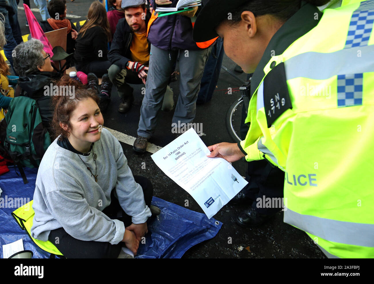 Eine Demonstrantin lesen Sie Abschnitt 14 der öffentlichen Ordnung handeln, die von der Polizei, bei der Millbank, an der Kreuzung mit der Großen College Street, während ein Aussterben Rebellion (XR) Protest in Westminster, London. Stockfoto