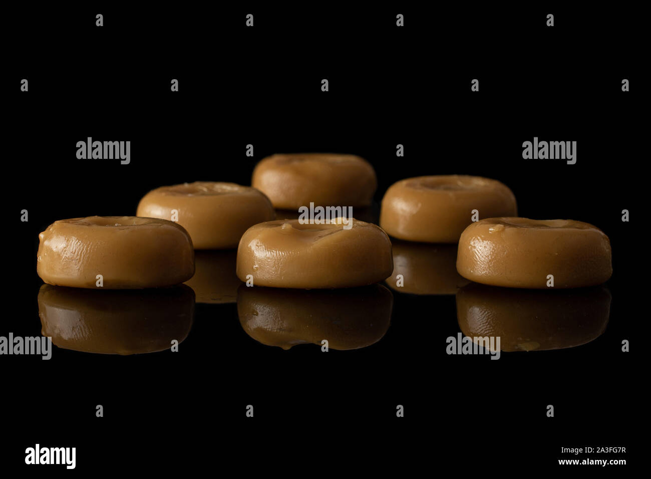 Menge ganze Caramel braun Candy auf schwarzem Glas isoliert Stockfoto