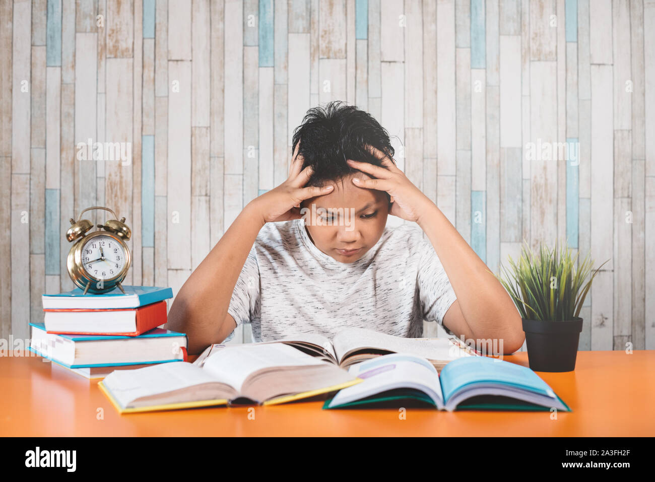 Betonte Student Learning hart mit Büchern in Prüfungen Vorbereitung überwältigt fühlen, während sein Kopf wegen der niedrigen und erschöpft Stockfoto