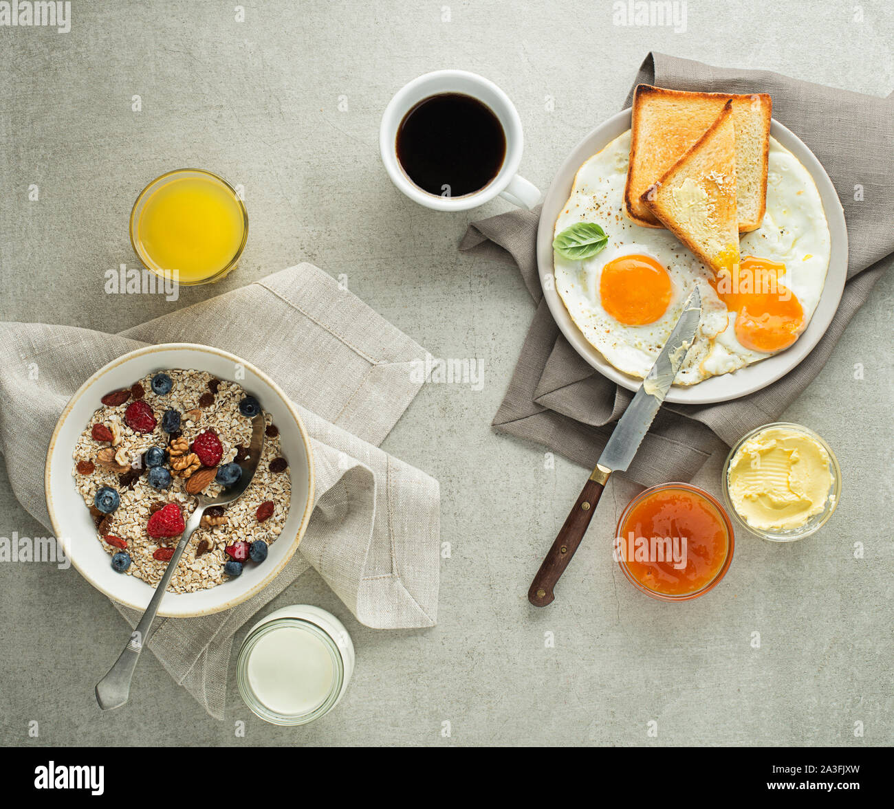Frühstück serviert mit Haferflocken und Obst, Spiegeleier mit Brot und Marmelade mit Butter auf dem Tisch Ansicht von oben. Heathy Frühstück essen Stockfoto