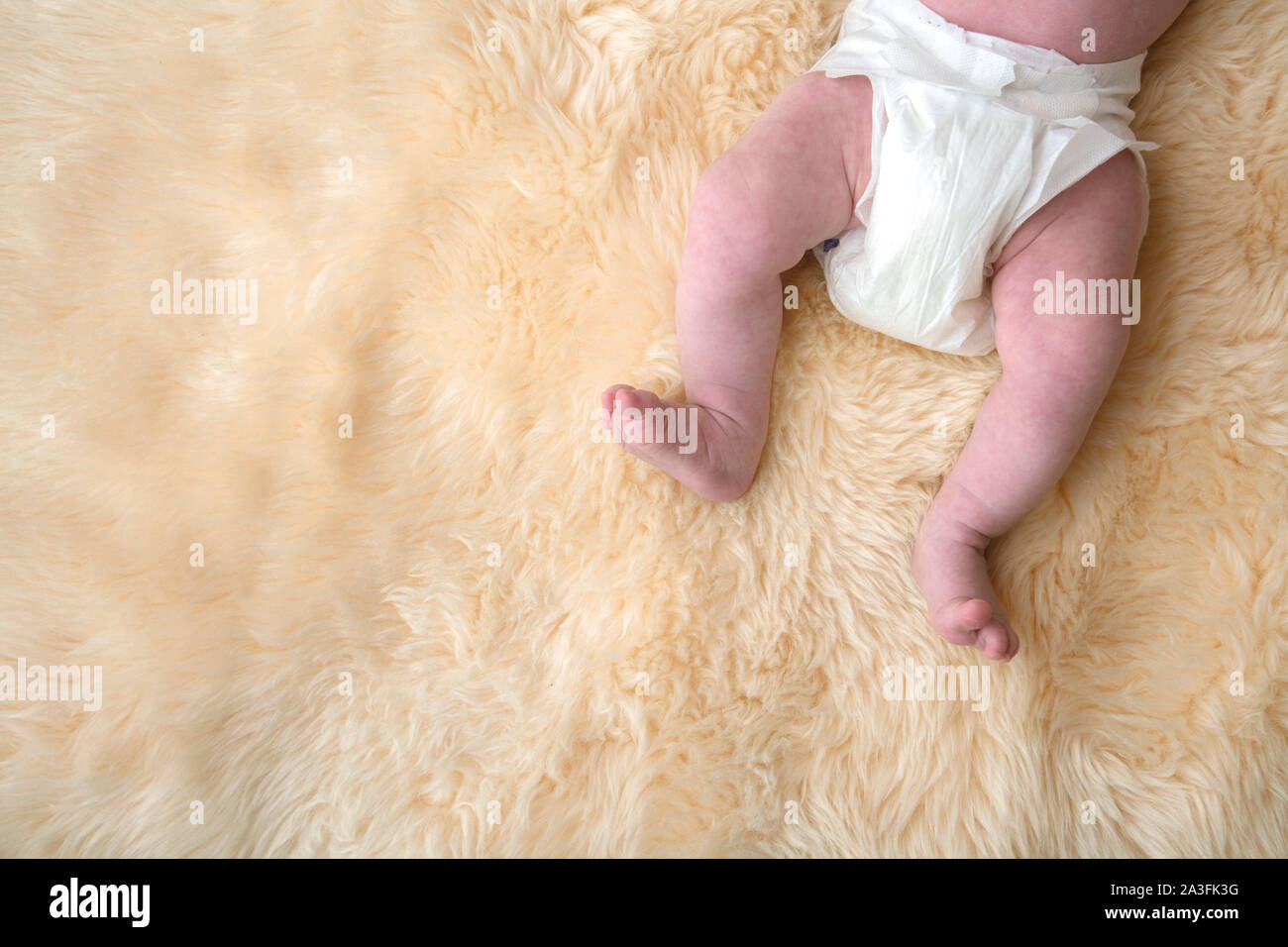 Neugeborenes Baby Beine mit weißen Windeln, Windel auf einem Fell Hintergrund. Stockfoto