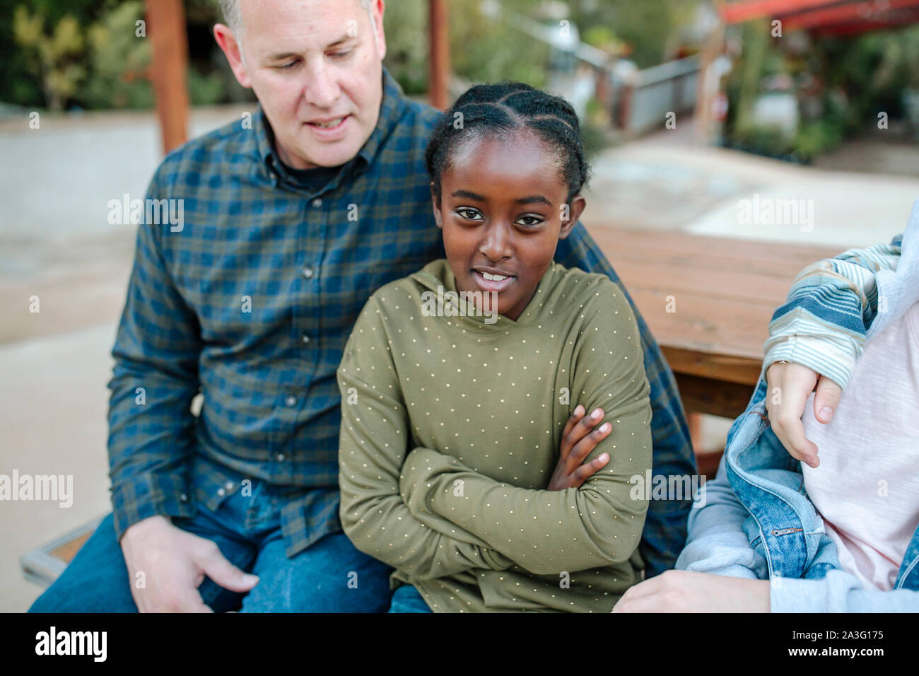 Mitte-40 Weiß Papa sitzt mit dem Lächeln 8-yr-old Black Tochter Stockfoto