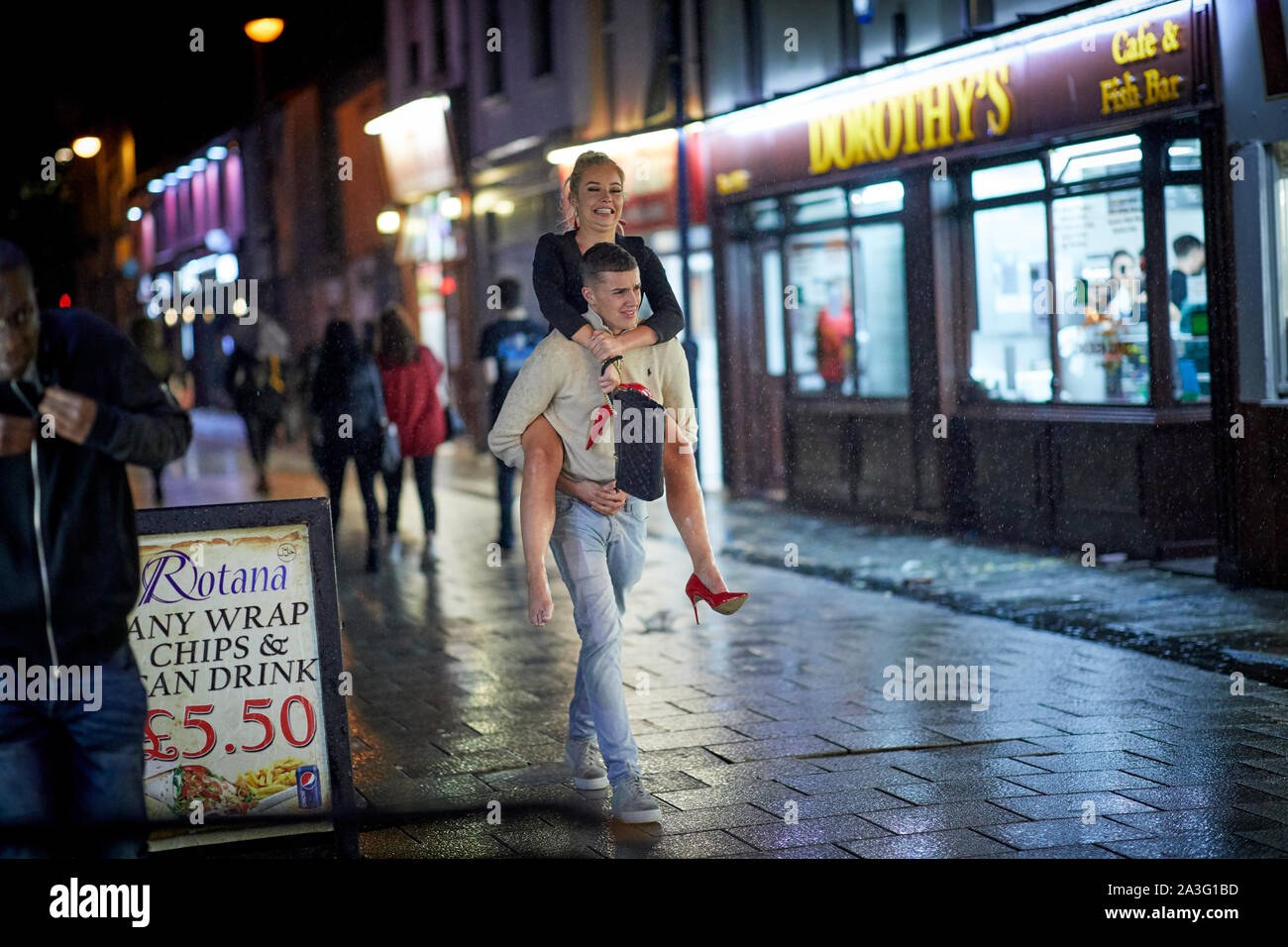 Cardiff Wales, Mann trägt eine Freundin auf seinem Rücken in einer Umarmung Stockfoto