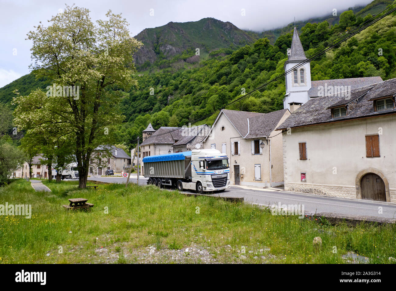 Lkw gehen durch ein kleines Dorf auf dem Weg nach Aspe-tal zum Col de Somport Tunnel und Spanien, Teil des starken Verkehrs entlang dieser Route Stockfoto