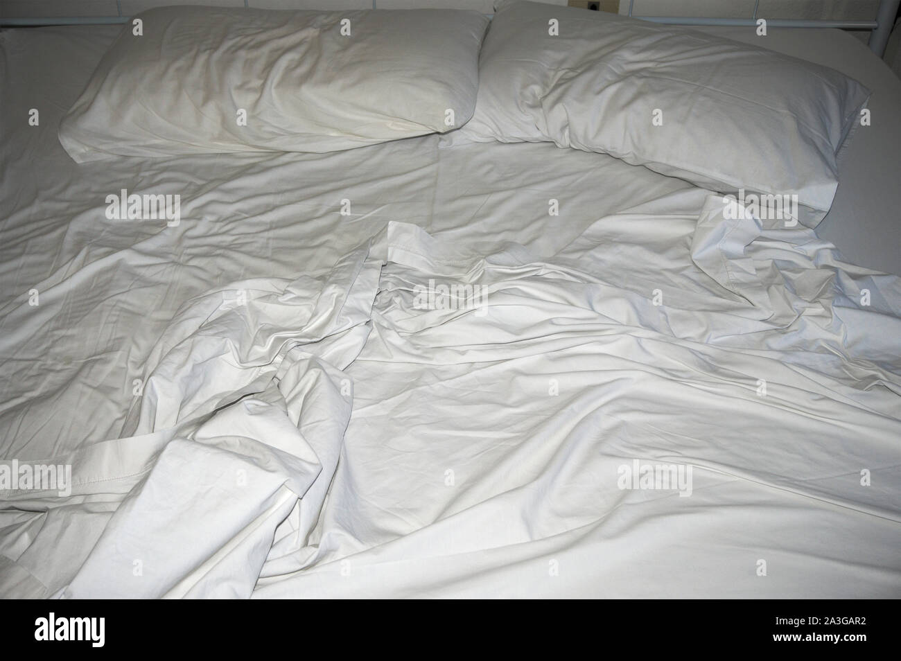 Ungemachten Bett mit Bettwäsche und Kissen Stockfoto