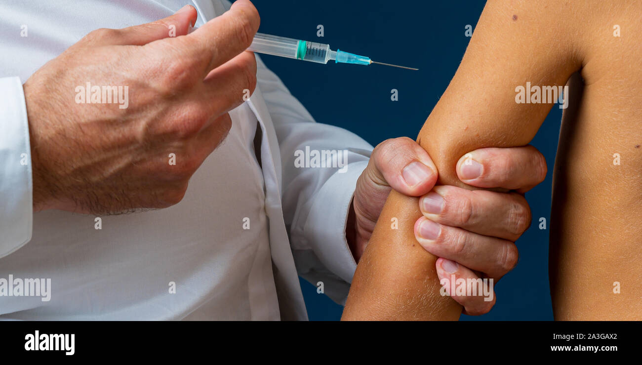 Nahaufnahme der pädiatrischen Arzt fest die Hand des Kindes über Ihn zu impfen. Stockfoto