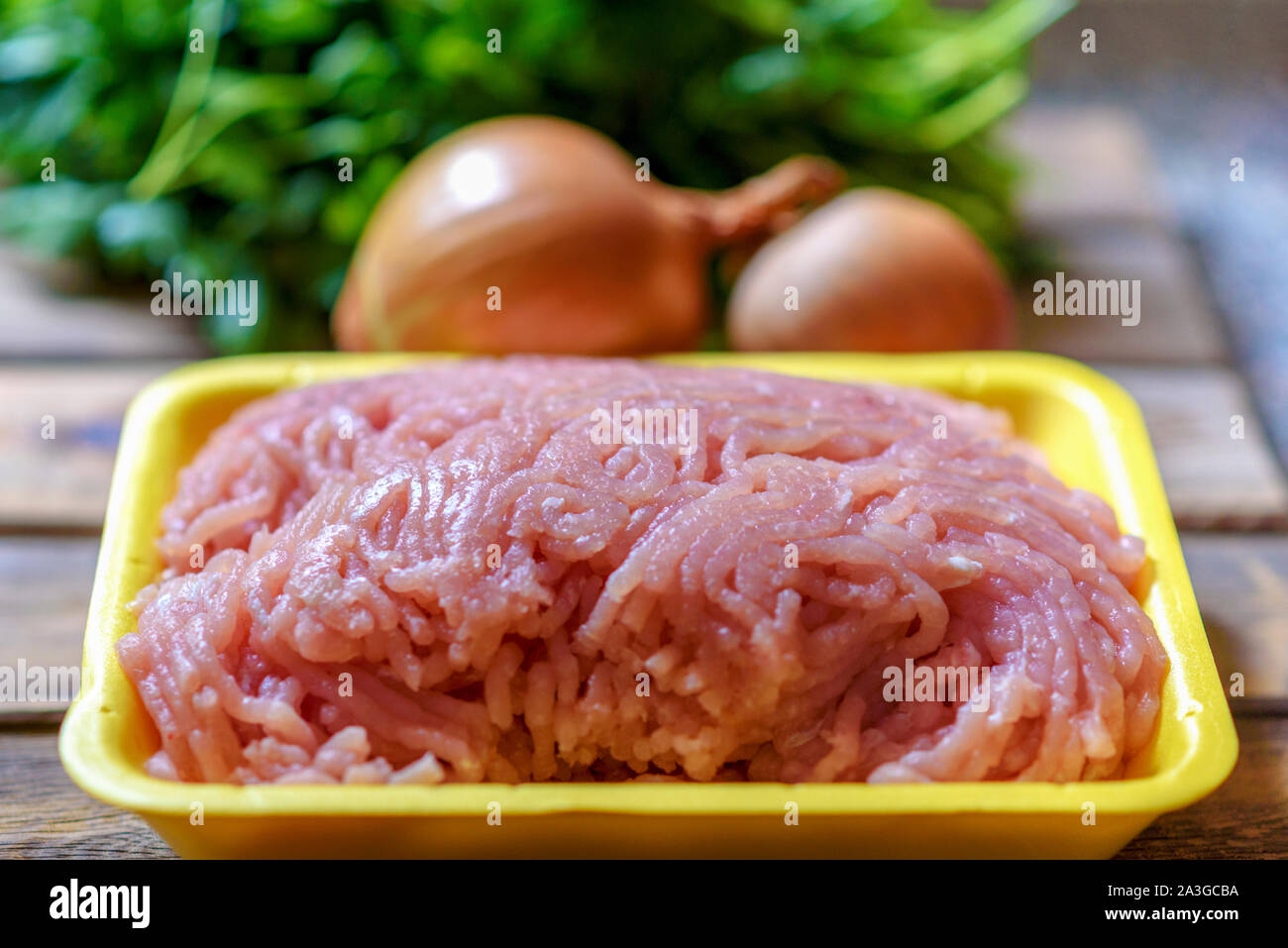 Rohes Hackfleisch, Zwiebel und Kräutern auf Holztisch. Blatt vor den Mund. Hackfleisch mit Zutaten zum Kochen auf Holz Hintergrund. Stockfoto