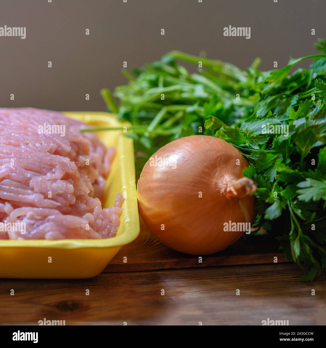 Rohes Hackfleisch, Zwiebel und Kräutern auf Holztisch. Blatt vor den Mund. Hackfleisch mit Zutaten zum Kochen auf Holz Hintergrund. Stockfoto