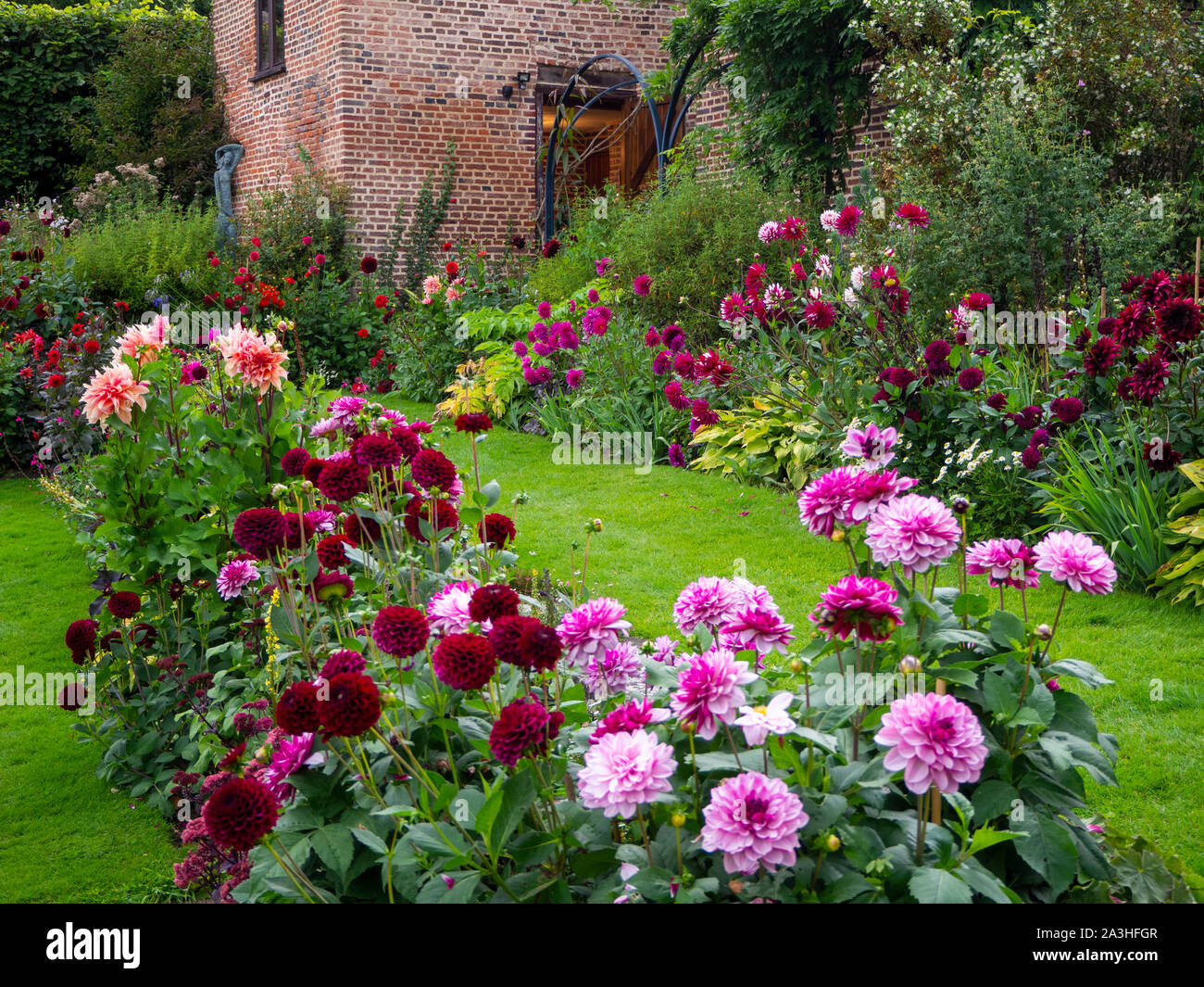 Chenies Manor versunkenen Garten Dahlie Anzeige auf einem September Abend. EIN Gras Weg führt zu den restaurierten Pavillon. Eine Leuchte in der alten Tür. Stockfoto