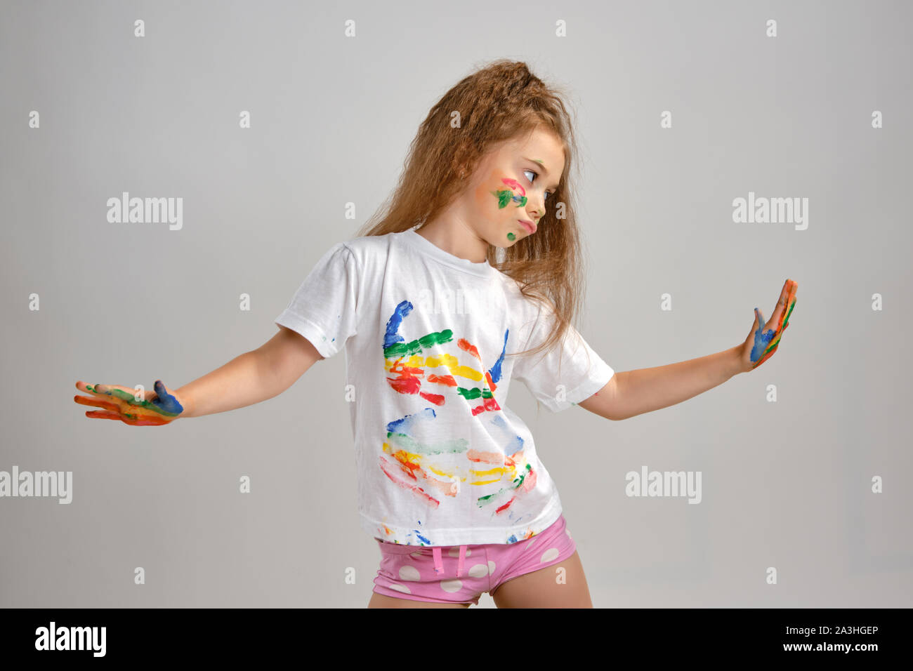 Kleines Mädchen in weiß lackiert t-shirt posiert stehen auf weißen isoliert und Gestikulieren mit ihren farbigen in verschiedenen Farben, Palmen und Gesicht. Kunst Stockfoto