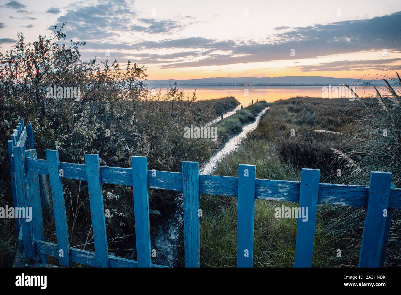 Holzzaun neben Averio's River bei Sonnenaufgang Stockfoto