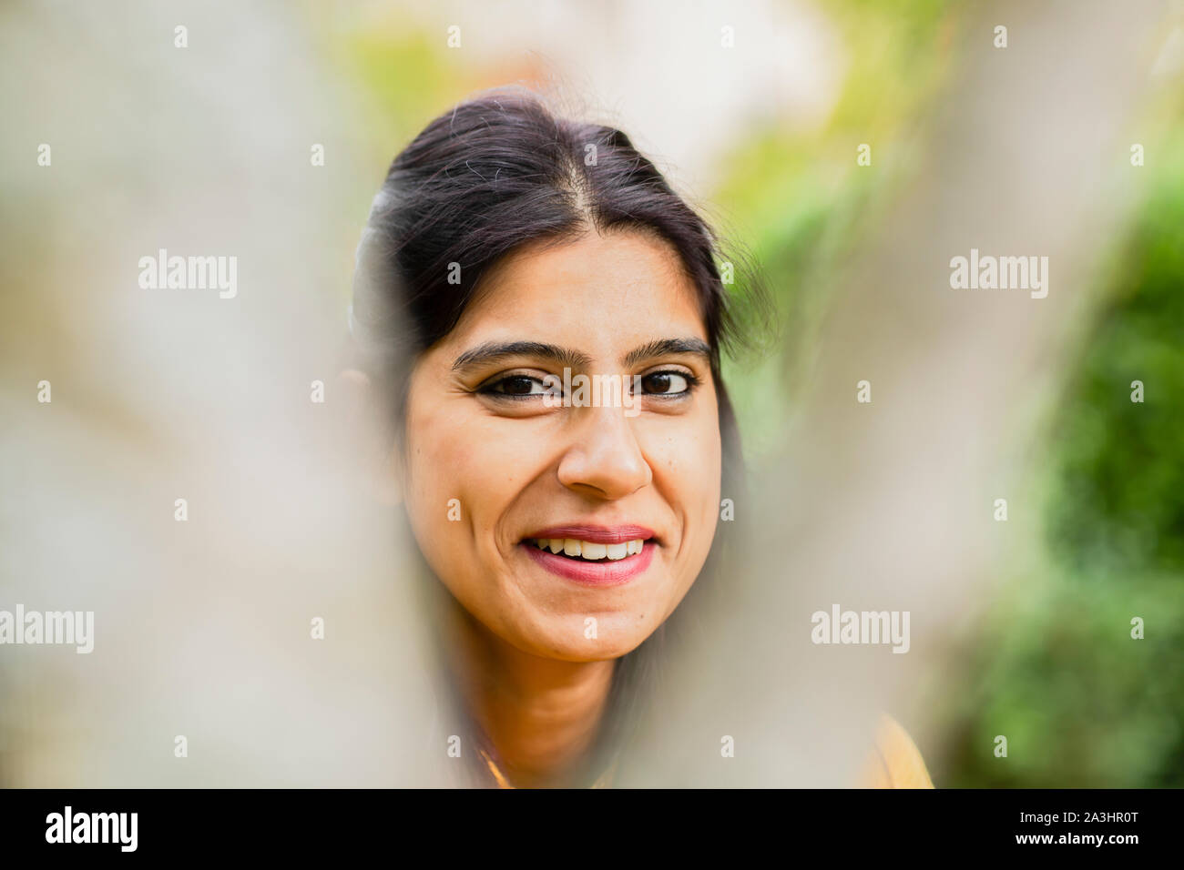 Junge Frau außerhalb lächelnd mit Unscharf vorne Stockfoto