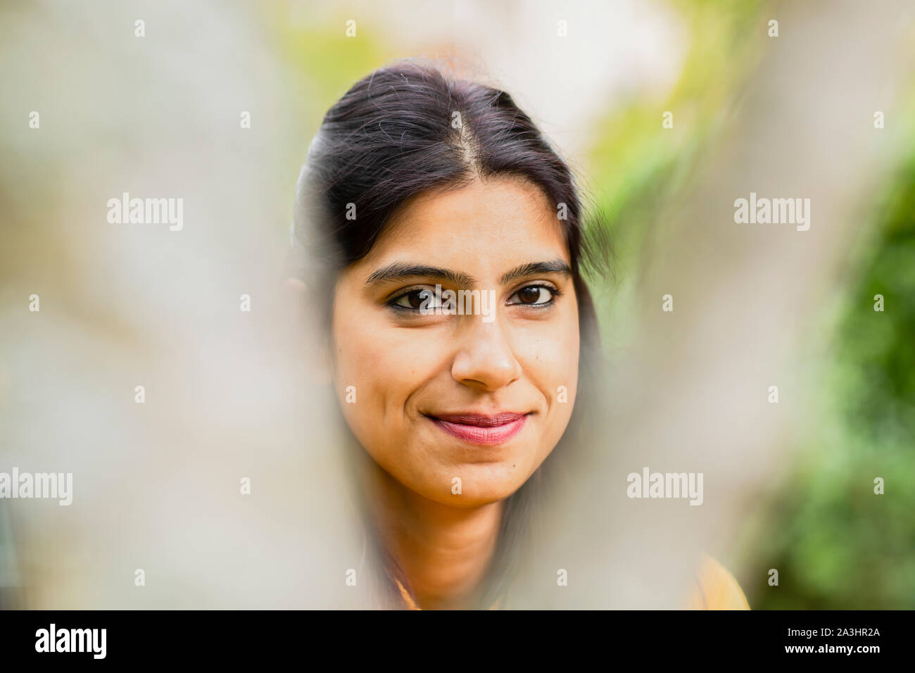Junge Frau außerhalb lächelnd mit Unscharf vorne Stockfoto