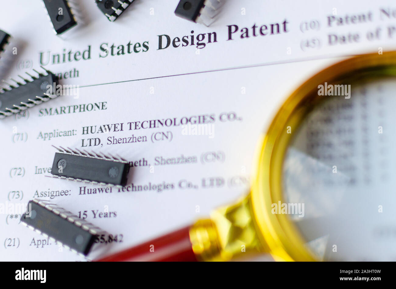 Die Nahaufnahme Foto von HUAWEI US-Patent, Lupe und Mikrochips. Chinesische Technologien sind Gegenstand der Untersuchung. Stockfoto