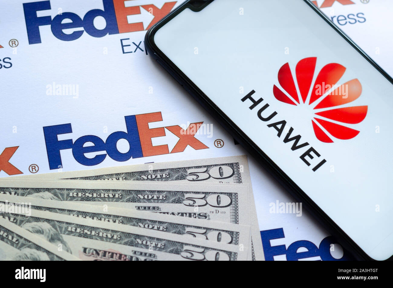 Huawei Smartphone mit Logo auf Paket FedEX logo mit US-Dollar. Diese konzeptuelle Foto zeigt USA-China trade Krieg und aktuelle Untersuchungen Stockfoto