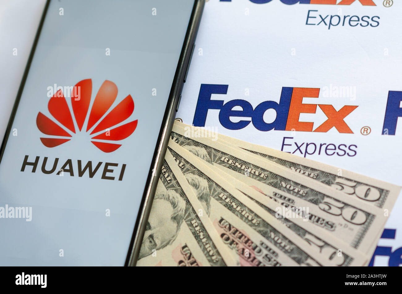 Huawei Smartphone mit Logo auf Paket FedEX logo mit US-Dollar. Diese konzeptuelle Foto zeigt USA-China trade Krieg und aktuelle Untersuchungen Stockfoto
