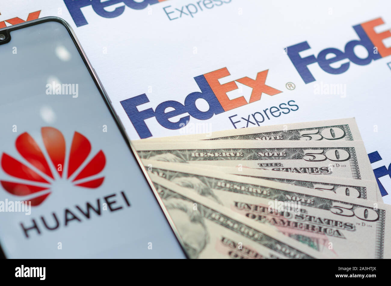 Huawei Smartphone mit Logo auf Paket FedEX logo mit US-Dollar. Diese konzeptuelle Foto zeigt USA-China trade Krieg und aktuelle Untersuchungen Stockfoto