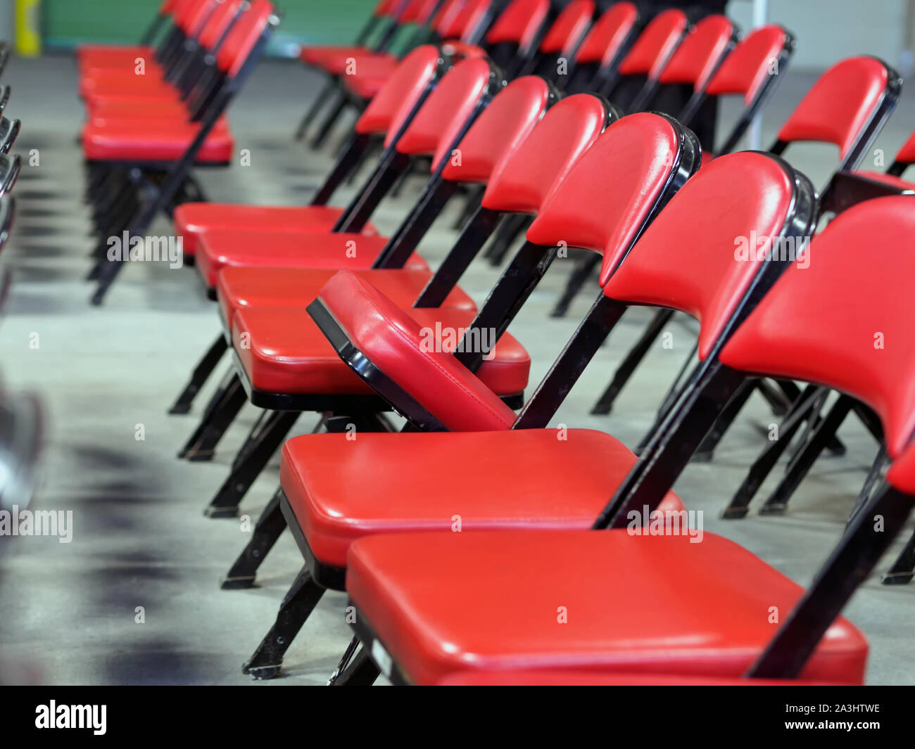 Reihen von roten Klappstühlen mit einem angehobenen Sitz. Stockfoto