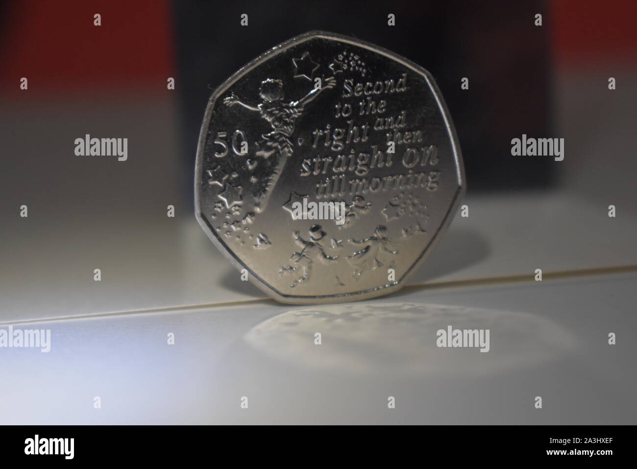 Silber 2019 erteilt Peter Pan 50 p Münze mit reflektierenden Licht, um Petrus und die Magische Sterne gegen eine helle und dunkle Farbe Hintergrund. Stockfoto