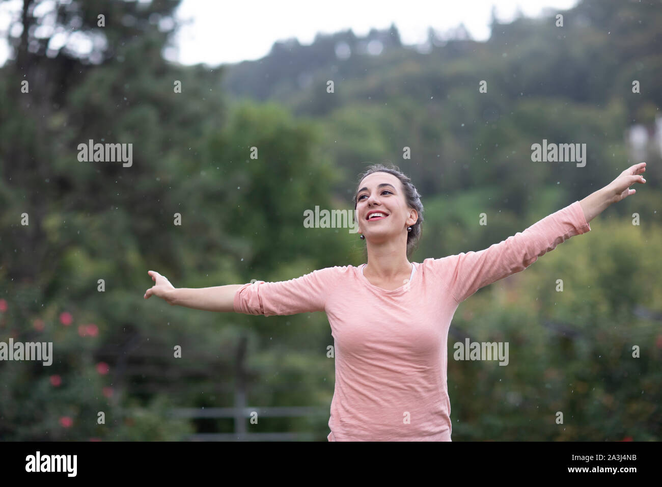 Junge Frau tanzen in einen Garten durch Regen Stockfoto