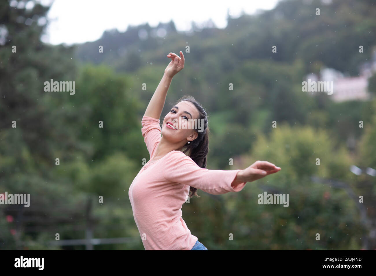 Junge Frau tanzen in einen Garten durch Regen Stockfoto