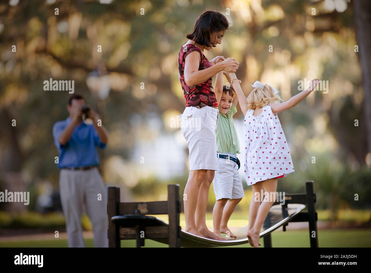 Mitte - erwachsene Frau, die mit ihrem kleinen Sohn und Tochter auf einem springenden Strahl. Stockfoto