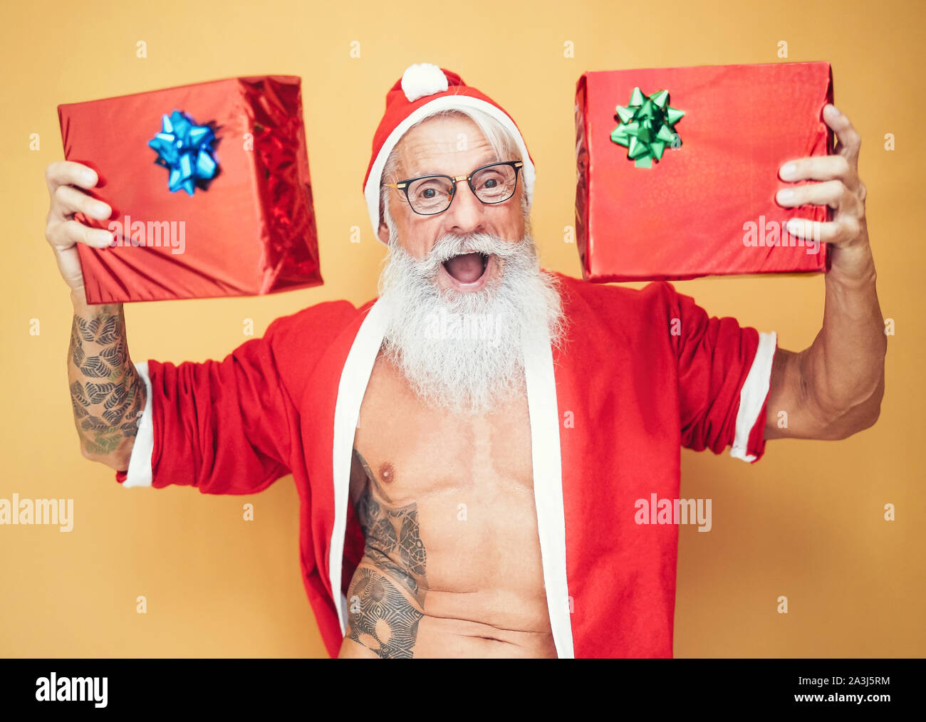 Tätowiert passen santa claus Holding Weihnachten Geschenke - trendige Bärtigen hipster Senior tragen xmas Kleidung Übersicht präsentiert Stockfoto