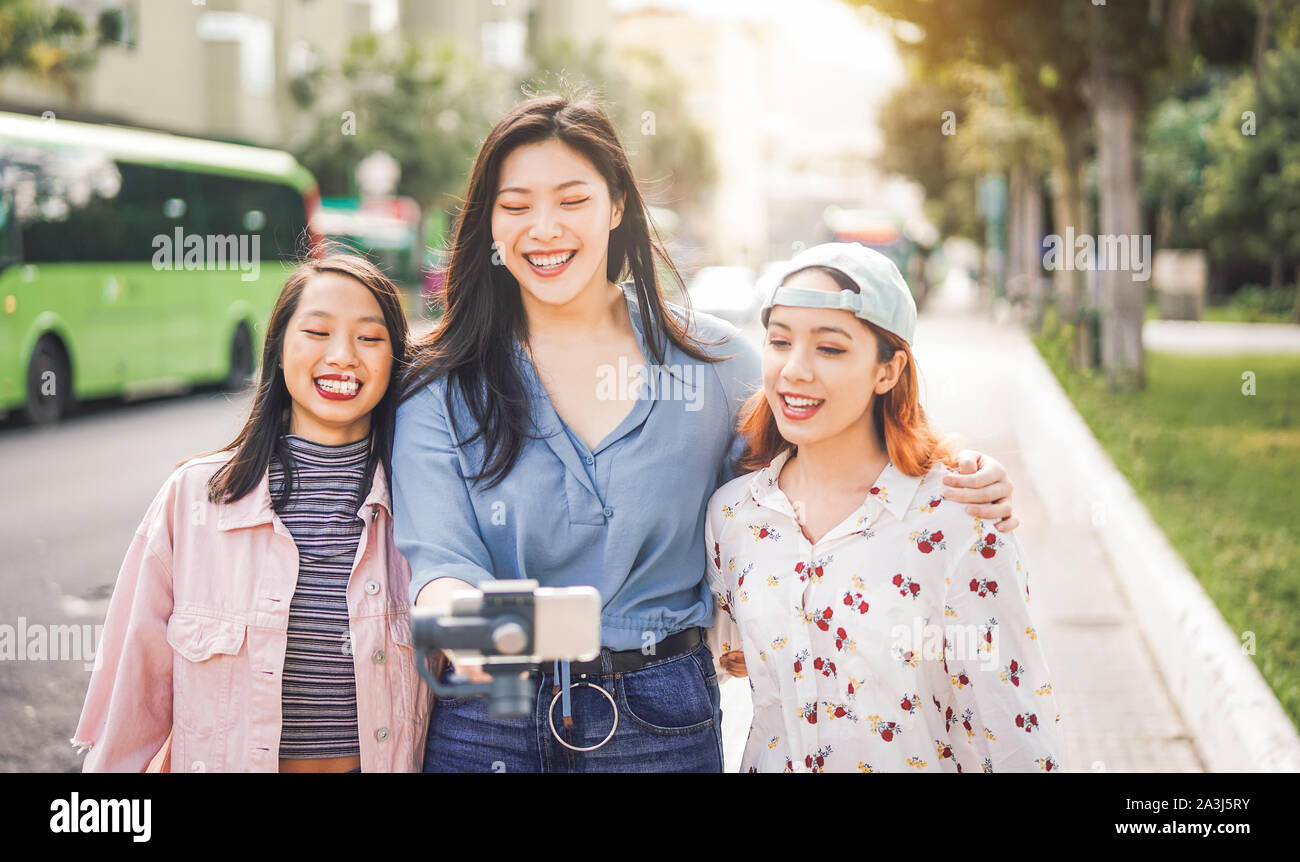 Happy asiatischen Freunden vlogging in City Bus station - trendige junge Leute mit Gimbal Smartphone outdoor Stockfoto