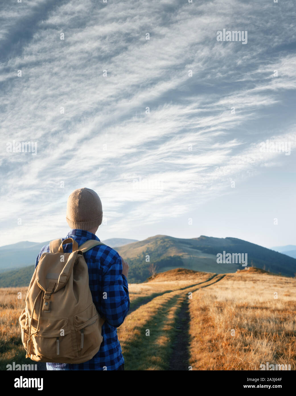 Mann mit Rucksack auf Berge Straße gegen den blauen Himmel Hintergrund. Travel Concept. Landschaftsfotografie Stockfoto