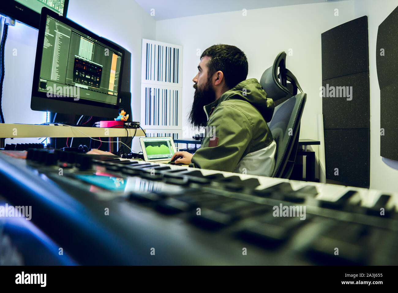 Junge DJ mit langen Bart produziert elektronische Musik in seinem Studio. Stockfoto