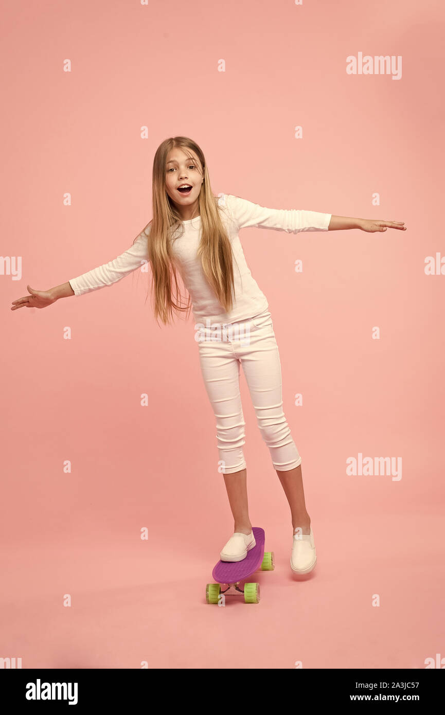 Regenerieren ihre Energie skateboarding. Adorable kleine Kind durchführen skateboarding Tricks auf rosa Hintergrund. Kleines Mädchen skateboarding auf Violett penny board Niedlich. Go skateboarding Day. Stockfoto