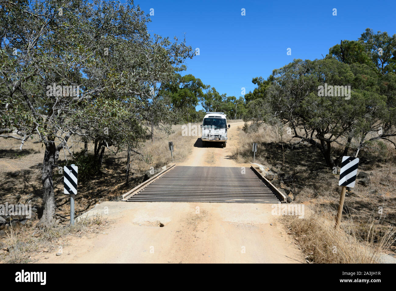 4WD Toyota Coaster Wohnmobil auf einem Feldweg über ein Vieh Raster im Outback in der Nähe von Ravenswood, Queensland, Queensland, Australien Reisen Stockfoto