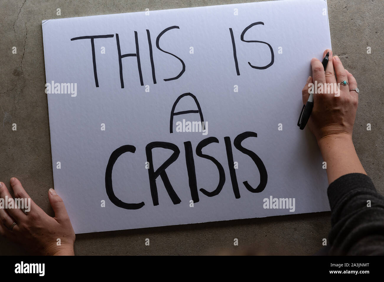 Anonym weiblich, Protest Zeichen, das sagt Dies ist eine Krise. Stockfoto