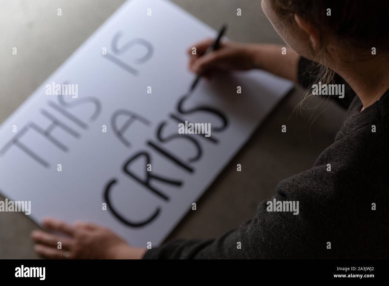 Anonym weiblich, Protest Zeichen, das sagt Dies ist eine Krise. Stockfoto