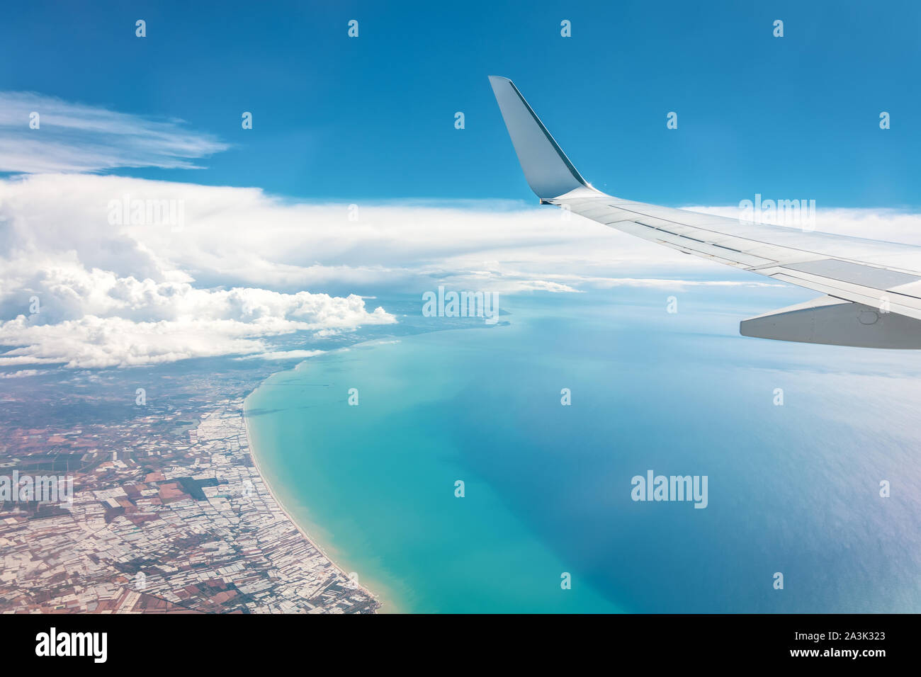 Blue Sky High wing Blick auf die Küste von einem Flugzeug, weit weg weiße Wolken Stockfoto