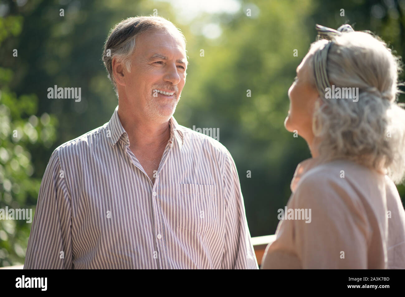 Grauhaarige bärtiger Mann lachend, während im Gespräch mit Frau Stockfoto