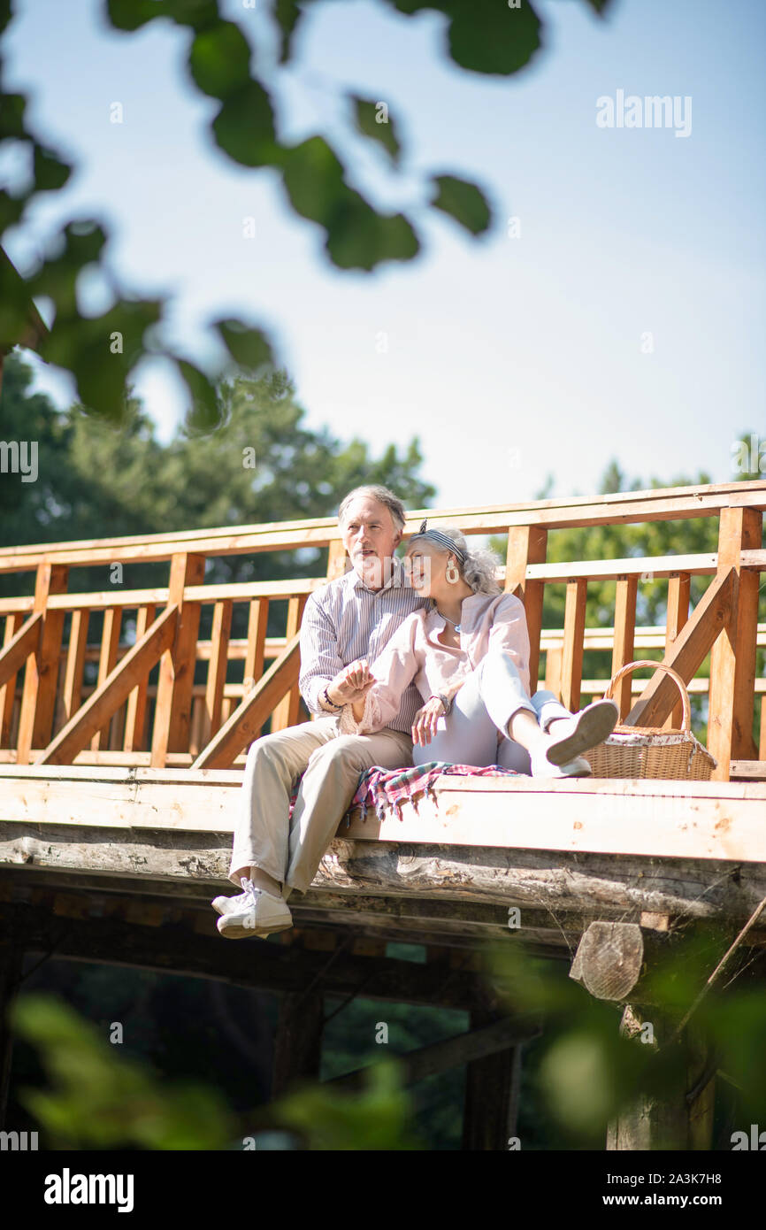 Paar sitzt auf der Brücke, während mit Picknick Stockfoto