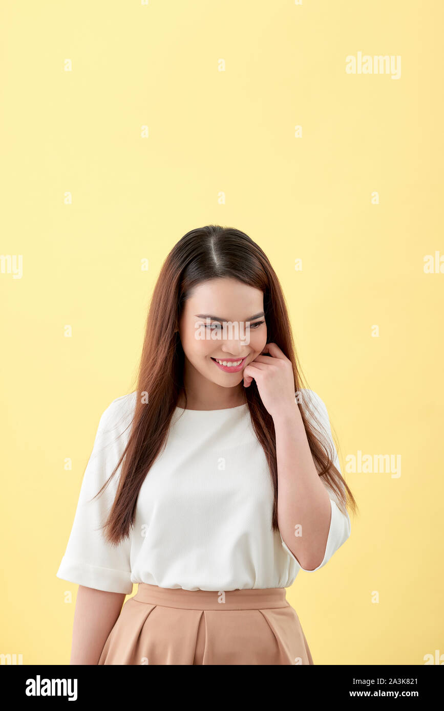 Schöne junge Frau mit langen schwarzen Haaren posiert auf gelbem Hintergrund Stockfoto