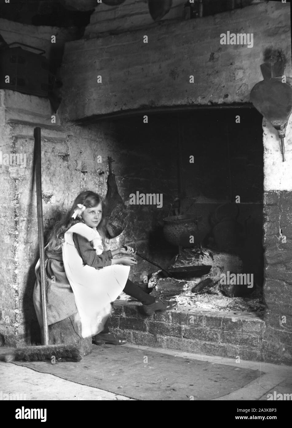 Ein junges Mädchen in einem Kittel mit einem Schwenk von einem Brand Herd in Newport, Wales. c 1907 Foto von Tony Henshaw Archiv Stockfoto