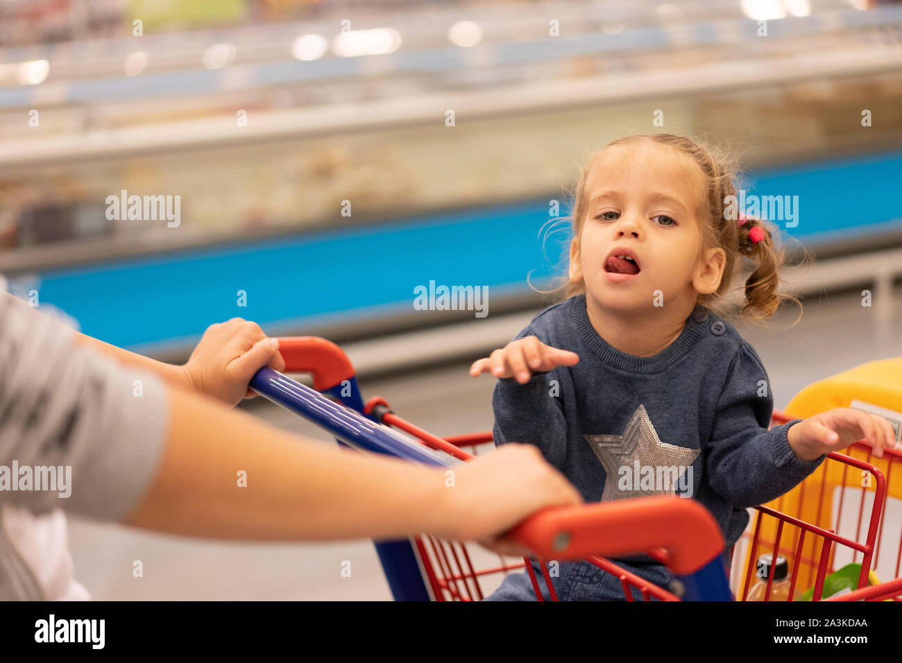 Mädchen und Frau mit Korb Katze auf Rädern in speichern. Mutter und Tochter im Supermarkt. Konzept die Käufer. Käufer Stockfoto