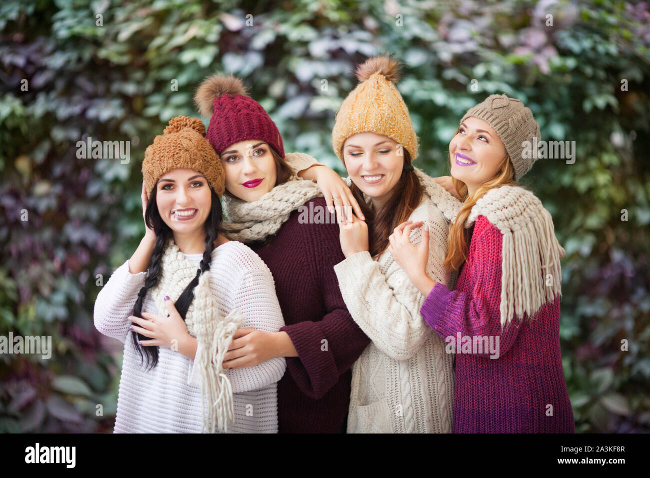 Vier Frauen, die besten Freunde kuscheln im Park in einem strickschal und Hüte. Stockfoto