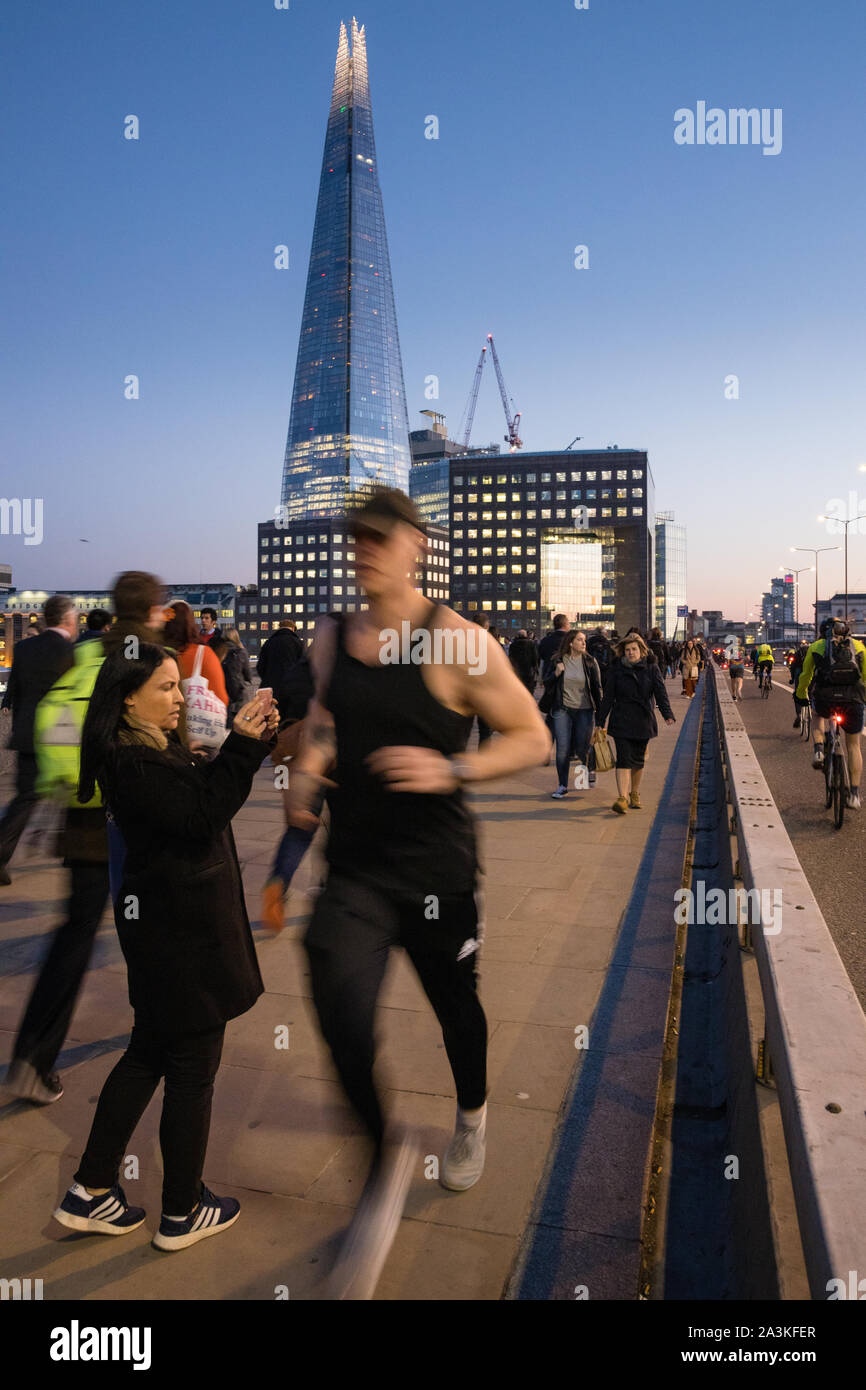 Pendler auf die London Bridge in der Dämmerung, mit dem Shard jenseits, London, England, Großbritannien Stockfoto